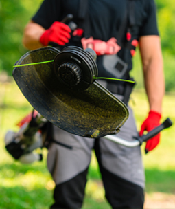 Une personne trononne un tronc d’arbre avec une trononneuse KOX, des copeaux de bois volent autour.